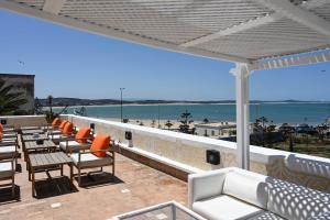a balcony with chairs and tables and a view of the beach at Madada Mogador in Essaouira