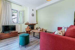 a living room with a red couch and a tv at Elies Villa Corfu in Áno Garoúna