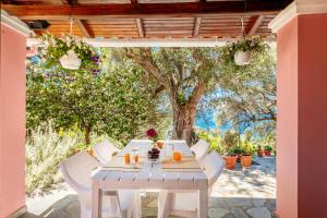 a white table and chairs on a patio with a tree at Elies Villa Corfu in Áno Garoúna