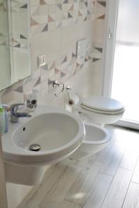 a bathroom with a white sink and a toilet at MARIS Apartments & Bedrooms in Alghero