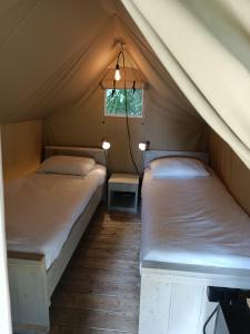 two beds in a tent with a window at Camping At Sea in Dronten