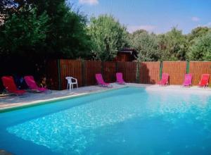 a swimming pool with pink chairs and a fence at LES CONILS - Gites et Chambres d'hotes in Saint-Pierre-de-Vassols