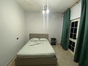 um quarto com uma cama num quarto com cortinas verdes em Tirana Apartment white em Tirana