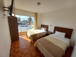 sypialnia z 2 łóżkami i dużym oknem w obiekcie Hostal Los Frayles w mieście Paracas