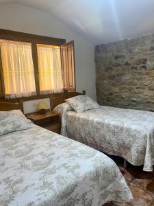 a bedroom with two beds and a stone wall at Peñasalve in Villamoñico