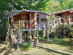 a tree house with a porch and a staircase at La cabane de l'oiseau in Couze-et-Saint-Front