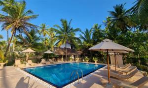 a resort swimming pool with chairs and an umbrella at Golden Beach Paradise in Tangalle