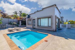 a villa with a swimming pool in front of a house at Vista Oceana – 4 Bedroom, Uvongo, Manaba Beach in Margate