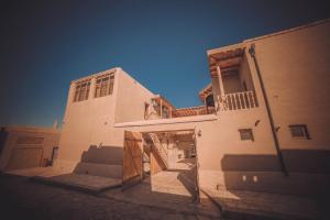a white building with stairs and a balcony at Oqilanur Guest House in Khiva