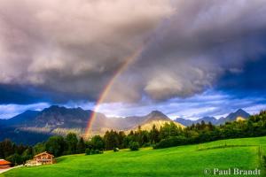 a rainbow over a green field with a house at Baldauf's Alpchalet in Oberstdorf