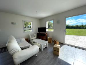 sala de estar con sofá blanco y TV en La Bourdetaise, en Le Bourdet