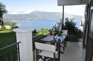 einen Balkon mit einem Tisch und Blick auf das Wasser in der Unterkunft Kommeno Bella Vista in Kommeno