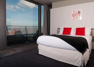 a bedroom with a bed with red pillows and a balcony at Midland Hotel in Morecambe