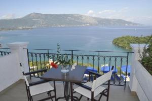 een tafel en stoelen op een balkon met uitzicht op het water bij Kommeno Bella Vista in Kommeno