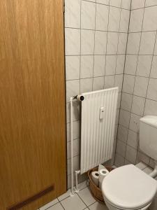 ein Badezimmer mit einem WC und einer Holztür in der Unterkunft Appartment 43 Haus Spiekeroog in Dornumersiel