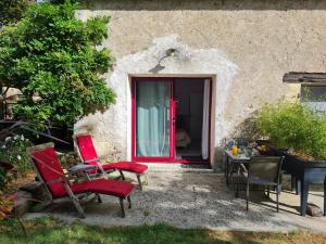 uma porta vermelha de uma casa com cadeiras e uma mesa em Au Clos du Coteau, Chambres d'Hôtes em Crotelles