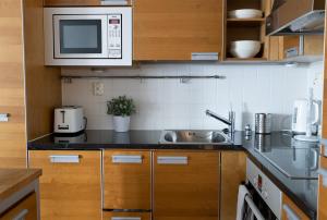 uma cozinha com um lavatório e um micro-ondas em 2ndhomes Luxury 1BR Kamppi Center Apartment with Sauna and Big Terrace em Helsinque