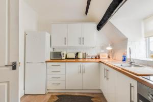 a kitchen with white cabinets and a white refrigerator at The Nook, Newly Available Relaxed 2 bed, Cotswolds in South Cerney