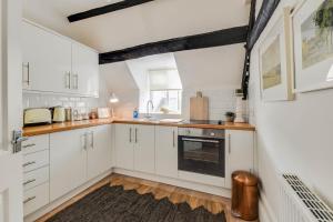 eine Küche mit weißen Schränken und einem schwarzen Backofen in der Unterkunft The Nook, Newly Available Relaxed 2 bed, Cotswolds in South Cerney