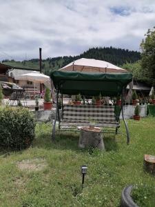 a large green umbrella on a bench in a yard at Popas Serbeca in Broşteni