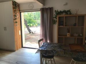 una camera con tavolo e porta scorrevole in vetro di LA BRINDILLE Petit mas provencal meublé de tourisme 3 étoiles 2-3 personnes 1 piece 30 m2 tout confort lisière foret jardin Jacuzzi Piscine a Saint-Paul-en-Forêt