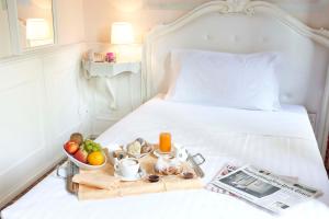 a bed with a tray of fruit and a newspaper at Hotel Villa Patriarca in Mirano