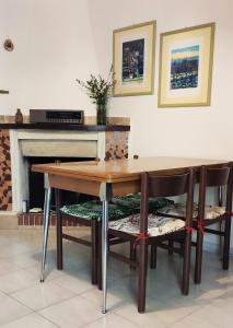 a dining room table with chairs and a fireplace at SA MENDUA E SA PRUNA casa al mare in Iglesias