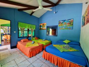 2 camas en una habitación con paredes azules en Cabinas Tortuguero Natural, en Tortuguero