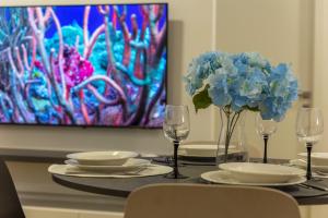 uma mesa com dois copos e um vaso de flores azuis em Poseidon Apartment em Izola