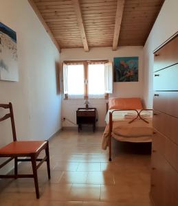a bedroom with a bed and a chair and a window at SA MENDUA E SA PRUNA casa al mare in Iglesias