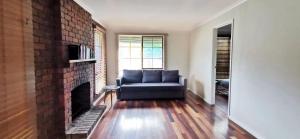 a living room with a couch and a brick fireplace at Spacious and cozy home next to Glen Waverley in Wantirna South