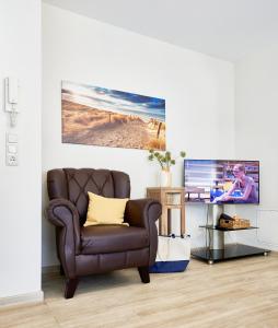 een woonkamer met een stoel en een flatscreen-tv bij Haus Pamir _ Fewo 27 in Cuxhaven