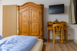 Schlafzimmer mit einem Bett und einem Schreibtisch mit einem TV in der Unterkunft Gasthaus Rössle in Bretzfeld