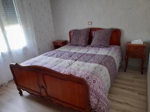 a bedroom with a large bed with a purple comforter at CHEZ VIVIANE in Celles-sur-Belle