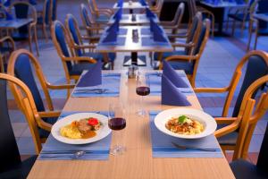 une longue table avec deux assiettes de nourriture et des verres de vin dans l'établissement Terme Topolsica - Hotel Vesna, à Topolšica