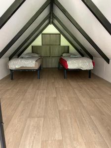 two beds in a attic with a wooden floor at Chalets Eureka & Bloemenduin Koksijde in Koksijde