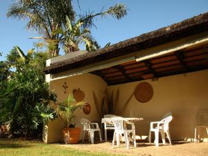 un patio con sillas blancas y una mesa en Peppertree House BnB and Self-catering en Fort Beaufort