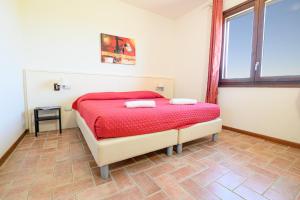 a bedroom with a bed with red sheets and a window at Residenza Principina in Principina Terra