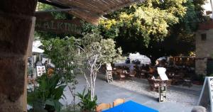 un patio esterno con tavoli, sedie e alberi di THE WALK INN apartments a Città di Rodi