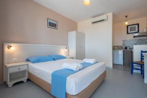 a bedroom with a large bed with blue pillows at Sunset Hotel in Agios Ioannis Kaspaka