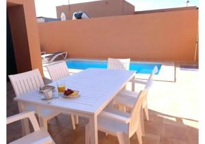 una mesa blanca y sillas con un bol de fruta. en Anahi Homes Corralejo - Villa Codeso 5, en La Oliva
