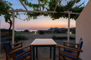 a table and chairs under a pergola with a sunset at Sunset Hotel in Agios Ioannis Kaspaka