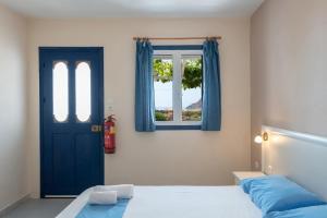 a bedroom with a blue door and a window at Sunset Hotel in Agios Ioannis Kaspaka
