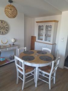 Un comedor con una mesa y sillas y un reloj. en Le diepplex de Sébelle, en Dieppe