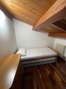 uma pequena cama num quarto com tectos em madeira em Casa Della Valle em Fano