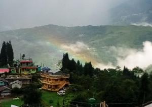 a rainbow in the sky over a mountain with houses at Syengden Nikunj in Darjeeling