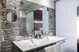 uma casa de banho com 2 lavatórios e um espelho grande em Hotel Ronda Lesseps em Barcelona