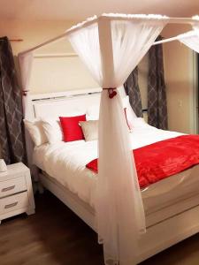 a bedroom with a white canopy bed with red pillows at Mountain Gem in McGaheysville