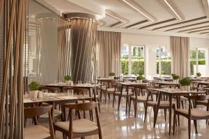 una sala da pranzo con tavoli, sedie e finestre di Atlantica Amalthia Beach Hotel - Adults Only ad Agia Marina Nea Kydonias