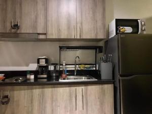 a small kitchen with a sink and a refrigerator at Cozy Bedroom FAME Condo Greenfield EDSA MRT Shaw in Manila